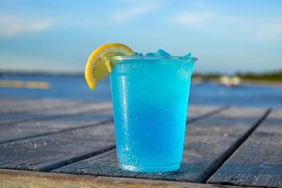 Close-up of drink in glass against blue water