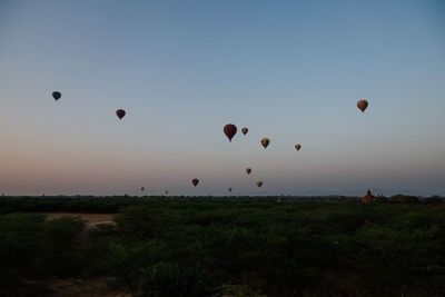 Hot air balloons flying over landscape against sky