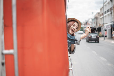 Portrait of smiling man with red umbrella in city