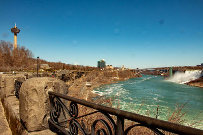 Bridge over river in city against clear blue sky