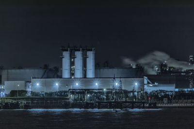 Illuminated factory against sky at night