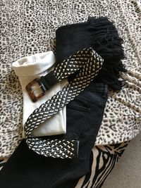 Coordinating black jeans with cream top, belt and scarf on animal print throw 