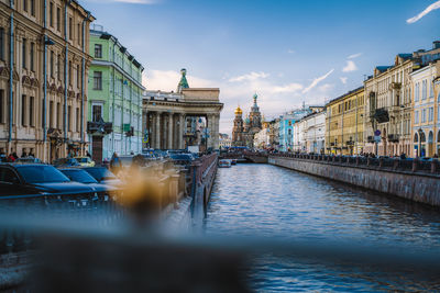 Canal amidst buildings in city against sky