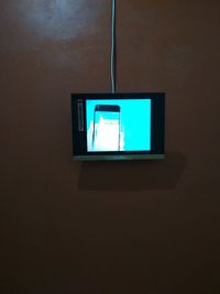 Low angle view of illuminated electric lamp on wall