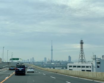 Cars on road by buildings against sky