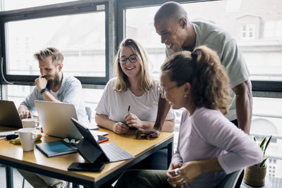 Happy female and male computer programmers planning strategy over laptop in startup company