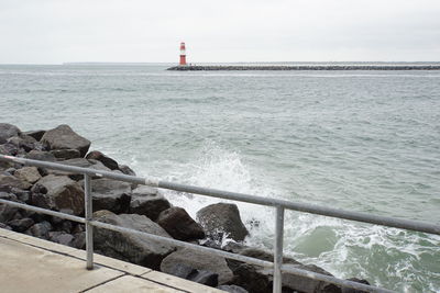 Lighthouse by sea against sky