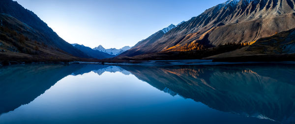 Scenic view of lake and mountains against blue sky