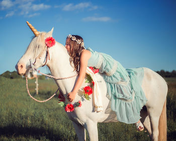 Girl riding horse on field