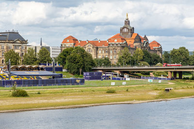 Buildings by river against sky in city