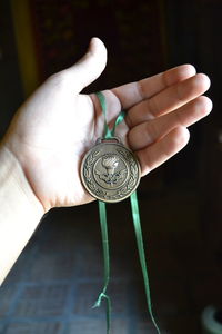 Close-up of hand holding clock against blurred background