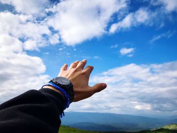 Cropped hand reaching sky