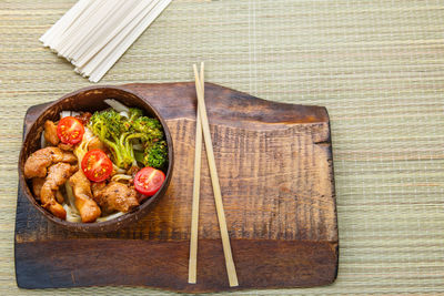 Chicken udon in japanese sauce on a plate of coconut chips on a chopsticks stand. horizontal photo