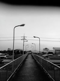 Street lights on bridge against sky in city