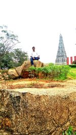 Man sitting on terrace against sky