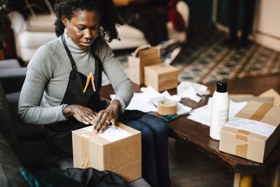 Young female hairdresser putting bar code label on box in barber shop