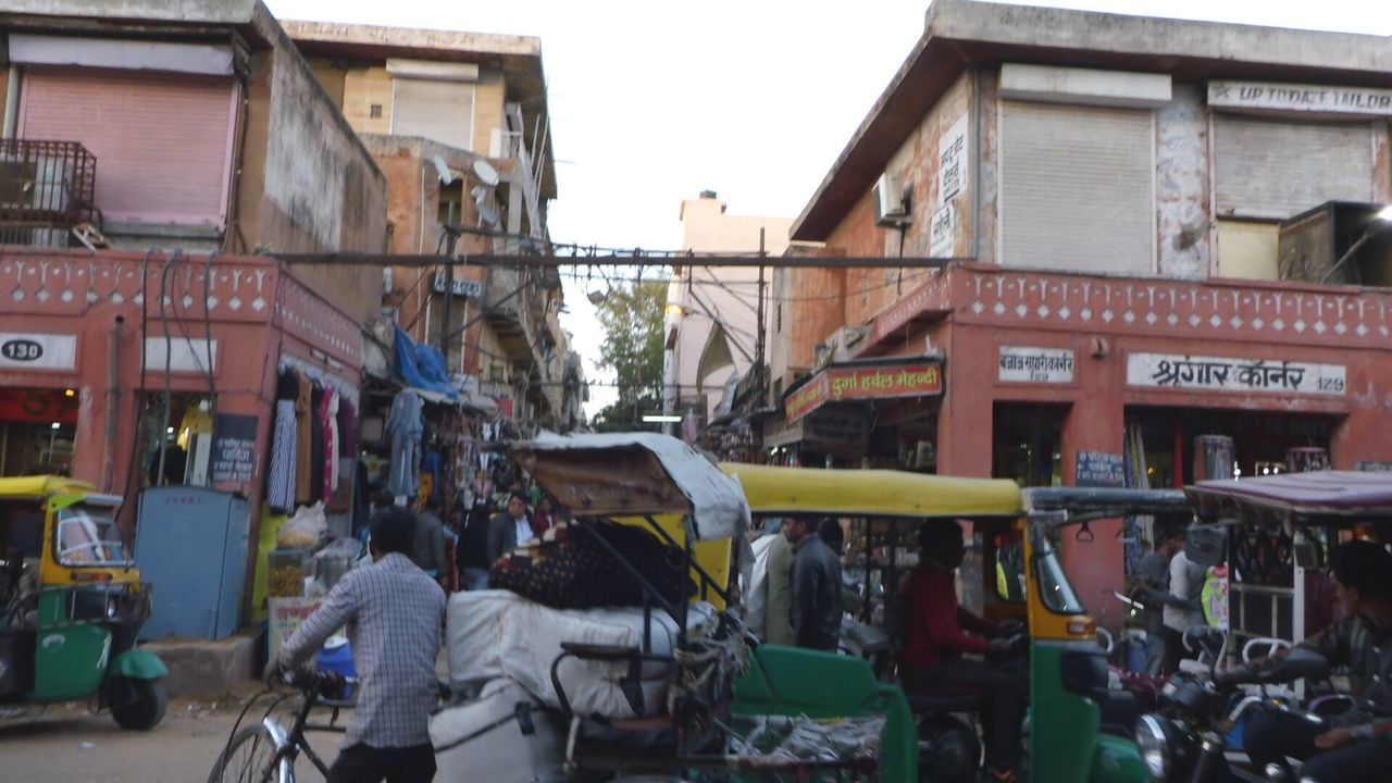 PEOPLE ON STREET BY BUILDINGS AGAINST SKY