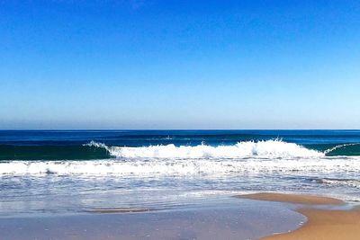 Scenic view of beach against clear blue sky