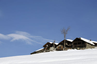 Houses on snow covered landscape against sky