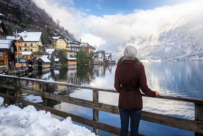 Rear view of woman looking at lake and mountain during winter in town