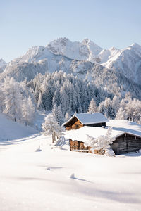 Winter mountain landscape with snowy forest and authentic alpine chalet