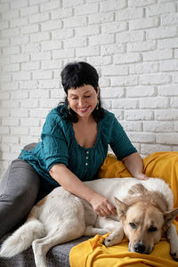 Happy woman with dog against wall