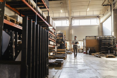 Businessman using digital tablet while walking at factory