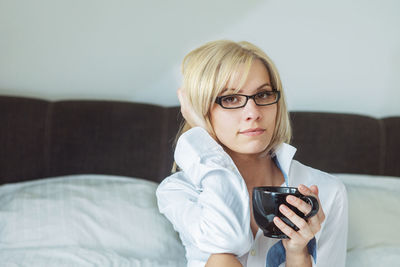 Portrait of woman drinking coffee on bed at home