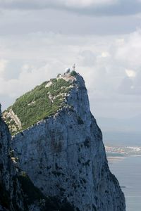 Cliff by sea against sky