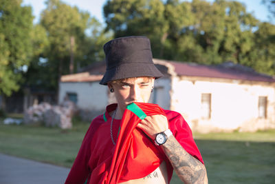 Portrait of teenage boy wearing hat standing against water