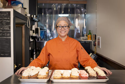 Portrait of woman standing with cupcakes at store