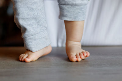 Low section of baby boy standing on hardwood floor