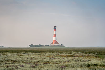 Lighthouse by sea against sky