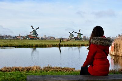 Woman sitting on windmills against sky