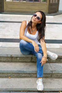 Casual style. stylish woman in sunglasses sitting on a stone staircase. she was