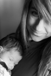 Portrait of smiling mother carrying sleeping baby