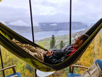 Man relaxing in hammock in a trehouse