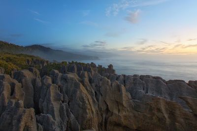 Cliff by sea against sky