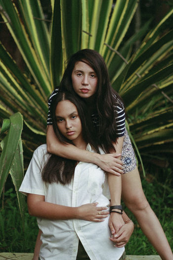 Portrait of two sisters standing against plants