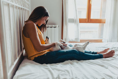 Side view of young woman using mobile phone at home