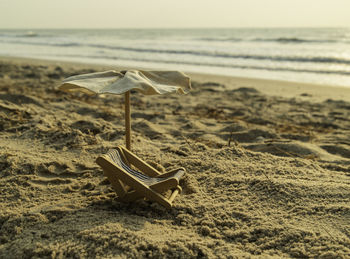 Deck chairs on sand at beach against sky