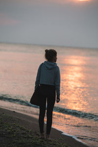 Rear view of woman walking on beach against clear sky
