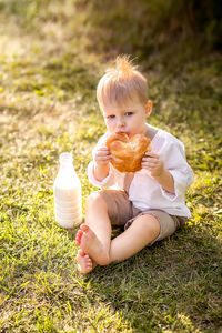 Cute boy eating food on field