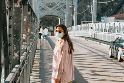 Side view of woman standing on bridge