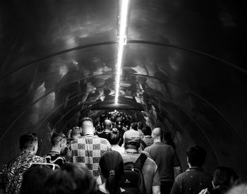 Rear view of people walking in illuminated tunnel