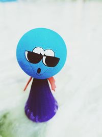 Close-up of sunglasses with toy against white background