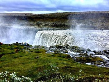 Scenic view of waterfall against sky