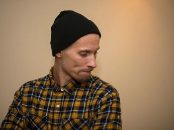 Portrait of young man looking away against gray background