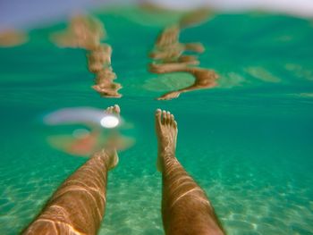 Low section of man swimming in turquoise sea