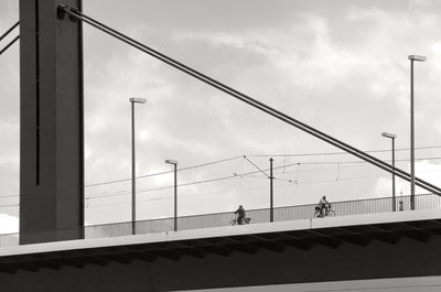 Low angle view of suspension bridge against cloudy sky